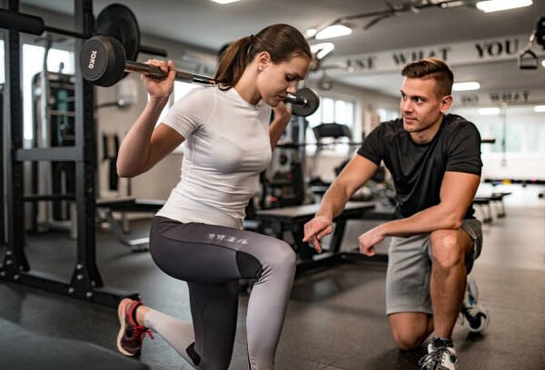 Fitness Instructor Guiding Young Woman When She Exercises. Rehabilitation vs. Personal Training: Striking the Balance for Athletes in NYC