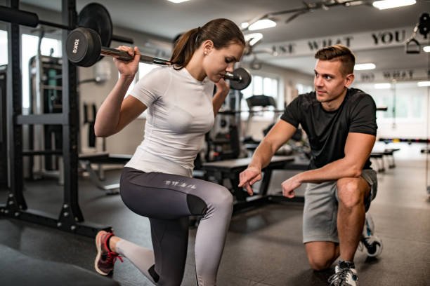 Fitness Instructor Guiding Young Woman When She Exercises. Rehabilitation vs. Personal Training: Striking the Balance for Athletes in NYC